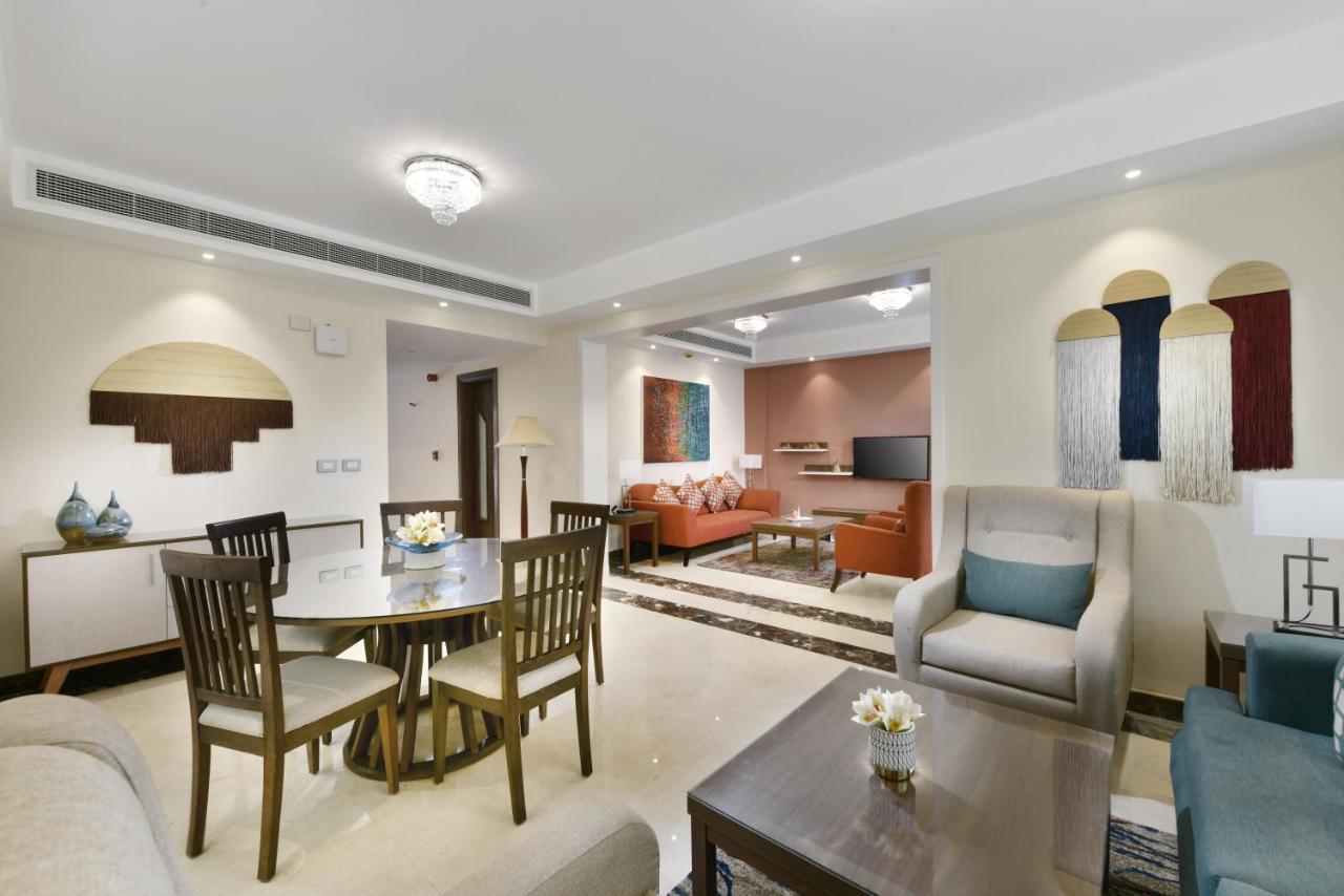 Tolip Resort El Galala Majestic Ain Sukhna Extérieur photo The photo shows a modern living room space that is elegantly designed. It features a seating area with a comfortable sofa and armchairs, complemented by a decorative coffee table. There is a dining table with several wooden chairs, providing a cozy a