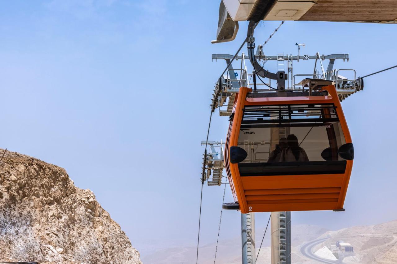 Tolip Resort El Galala Majestic Ain Sukhna Extérieur photo The photo shows an orange gondola or cable car hanging on a cable system. The gondola appears to be suspended in the air above a rocky landscape, with a clear sky in the background. There are supporting cables and structures visible, indicating that 