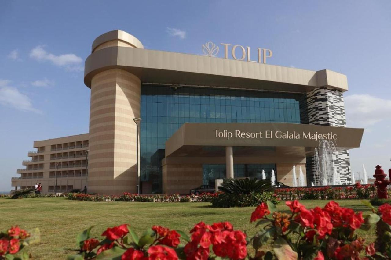 Tolip Resort El Galala Majestic Ain Sukhna Extérieur photo The photo shows a modern hotel building named "Tolip Resort El Galala Majestic." The structure features a distinctive architectural design with large glass windows and a prominent entrance. Surrounding the building are well-maintained lawns and vibra