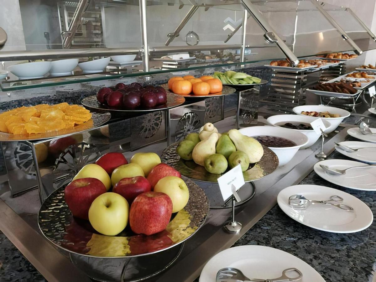 Tolip Resort El Galala Majestic Ain Sukhna Extérieur photo The photo displays a buffet setup featuring an assortment of fresh fruits arranged on several tiered trays. There are red and green apples, pears, grapes, and oranges. Adjacent to the fruit display, there are several bowls containing various other fo